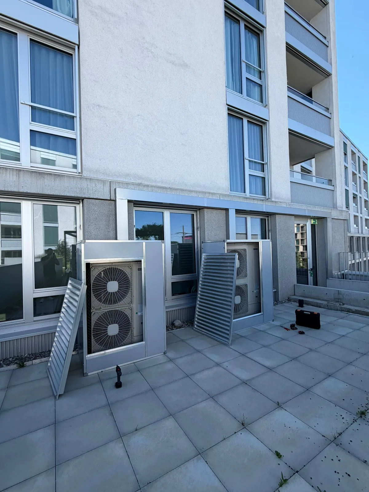 Zwei Aussengeräte mit geöffneten Verkleidungen an einer Gebäudefassade